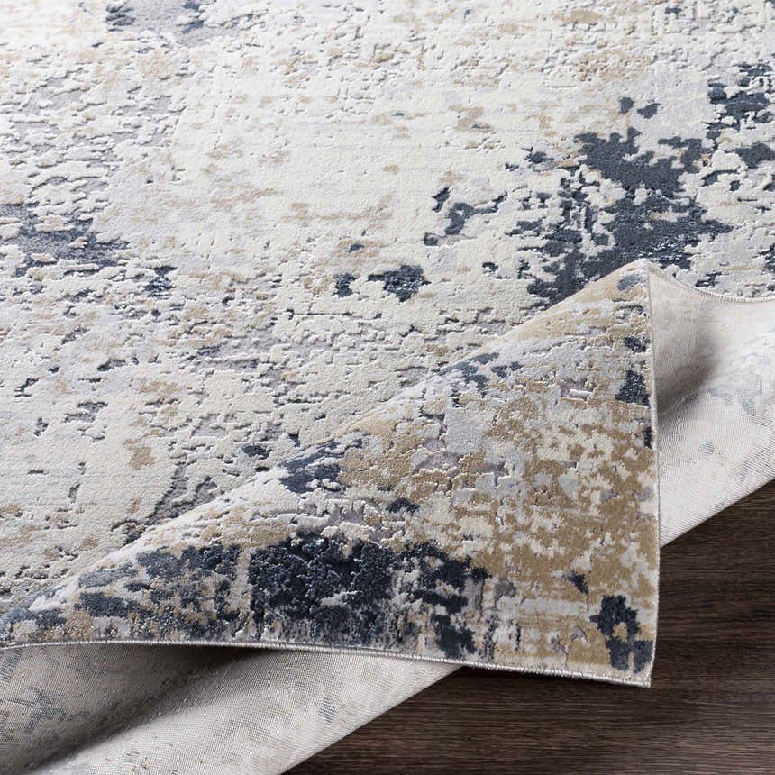 Close-up of the Ryhill Textured Luxe Area Rug showing charcoal, beige, and gray abstract pattern and woven texture. Fold