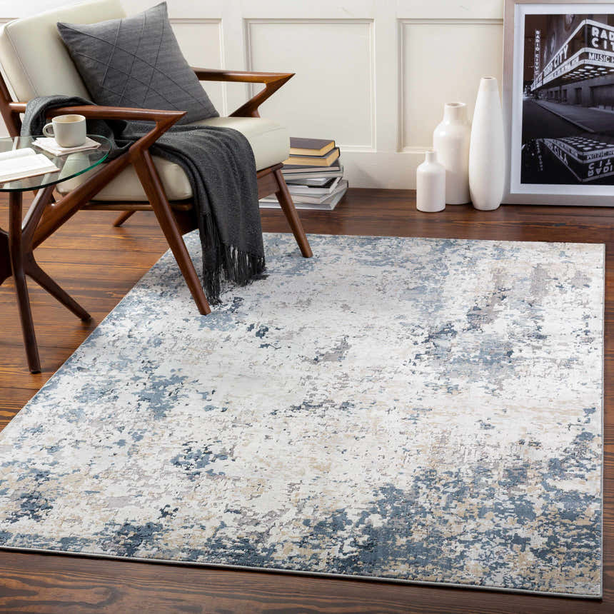 Living room scene with a Ryhill Textured Luxe Area Rug in charcoal, blue, beige, and gray tones. Modern chair and decor. Roomscene-Rectangle