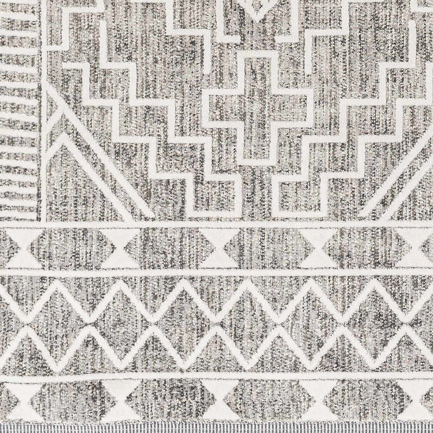 Close-up of the Reyn Area Rug, showcasing its geometric pattern in dark gray, light gray, and white tones. Swatch