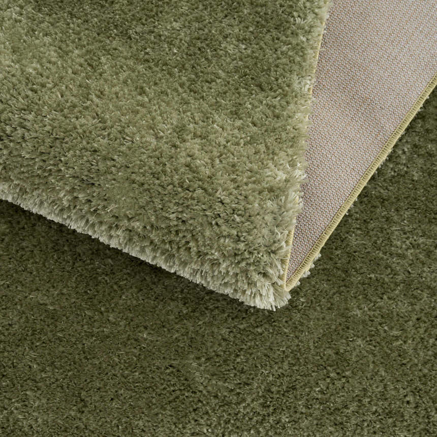 Close-up of the plush Heavenly Solid Green Rug showing its shag texture and backing. Fold