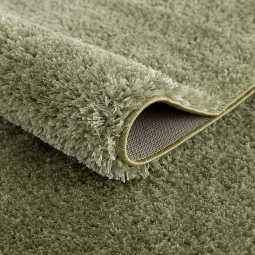 Close-up of the plush texture and backing of the Heavenly Solid Green Plush Rug. Fold