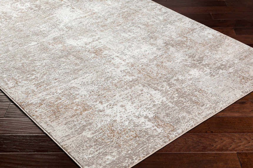 Close-up of the Bruna Area Rug showing its cloud gray, ivory, and multi brown abstract pattern and machine woven texture. Corner