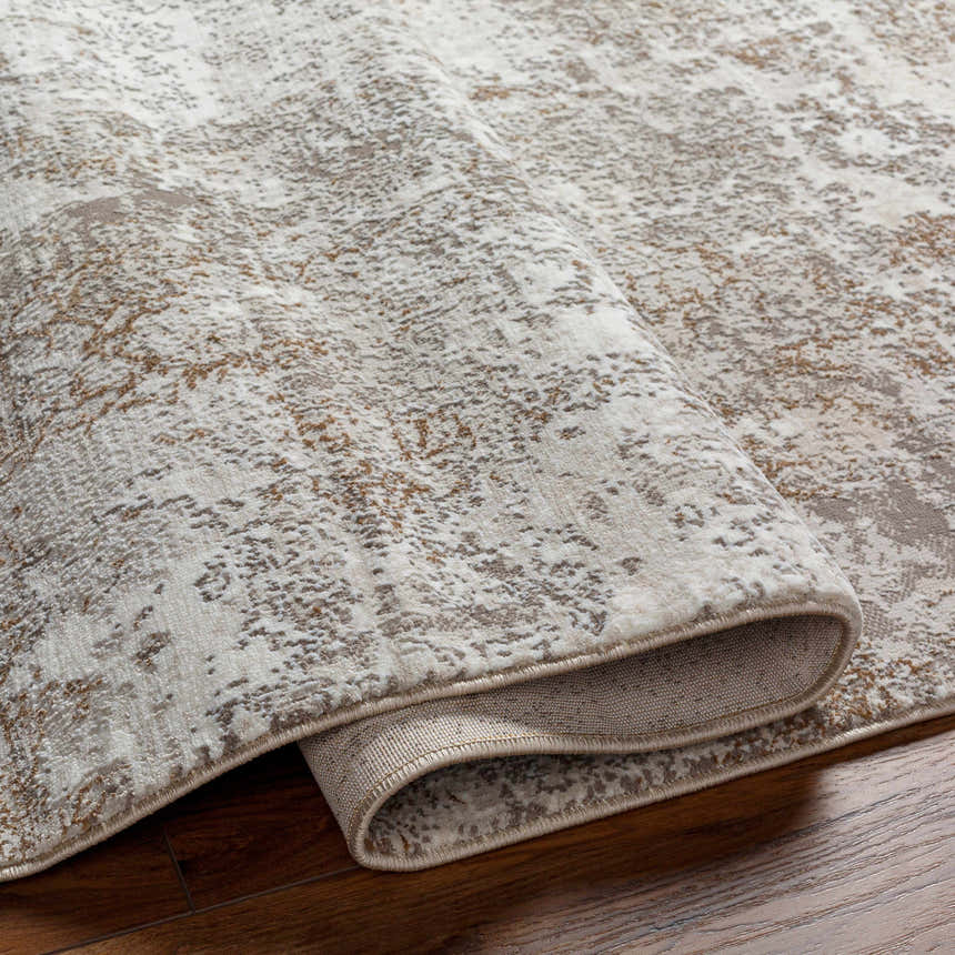 Close-up of the Bruna Area Rug showing its cloud gray, ivory, and brown abstract pattern and machine-woven construction. Fold