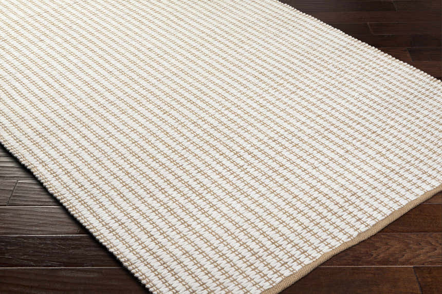 Close-up of the hand-woven Ieuan Area Rug in beige and bone. Farmhouse style rug with a subtle geometric pattern. Corner