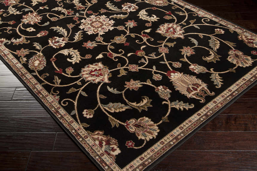 Close-up of the Salona Luxe Black Rug, showcasing its floral pattern and colors: black, beige, coral, and brown. Corner
