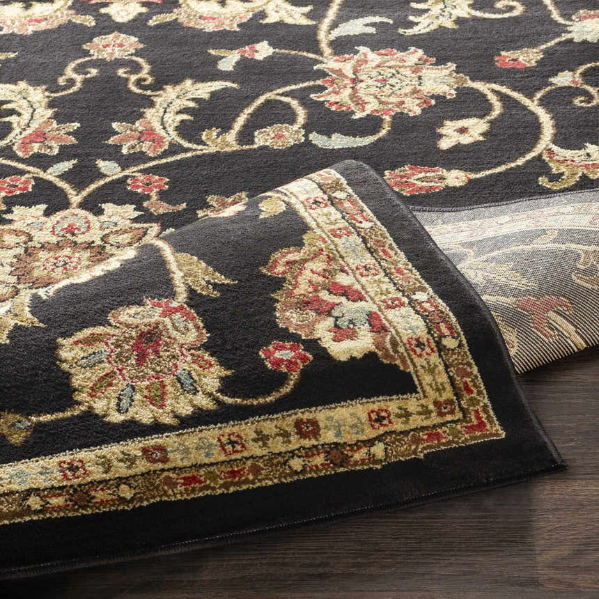Close-up of the Salona Luxe Black Rug showing its floral pattern, beige border, and soft, textured pile. Fold