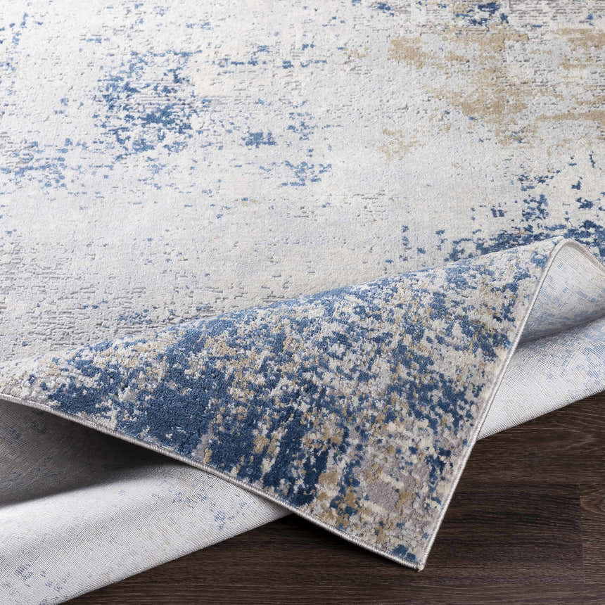 Close-up of the Sapcote Textured Luxe Area Rug showing its charcoal, blue, and beige abstract pattern and textured weave. Fold