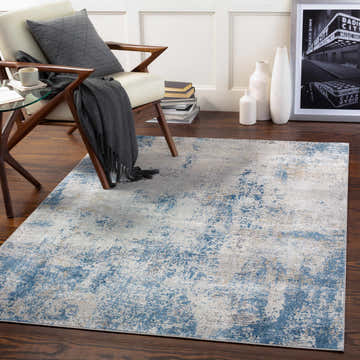Living room scene with Sapcote Textured Luxe Area Rug in light blue, beige, and gray under a modern chair on a dark wood floor. Roomscene-Rectangle