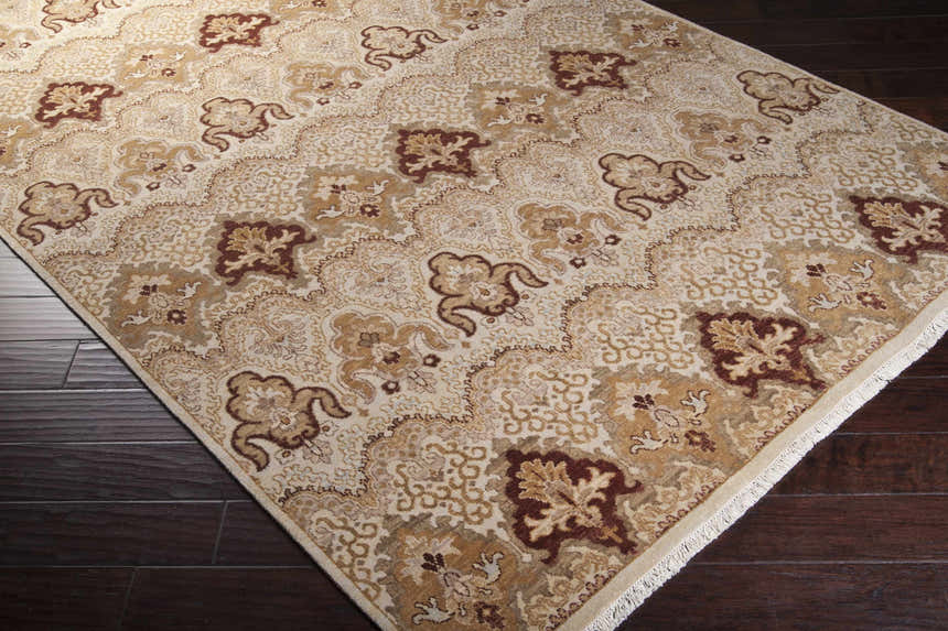 Close-up of the Saratoga Area Carpet. Traditional rug with brick red, camel, and light brown floral pattern on a light background. Corner