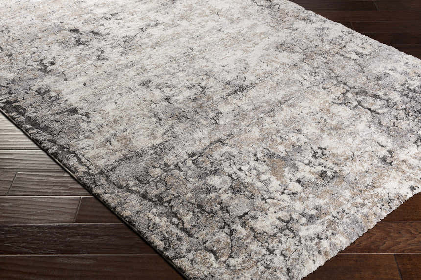 Close-up of the Satsop Rock Pattern Thick Rug showing its black, charcoal, gray, ivory, and tan colors and textured design. Corner