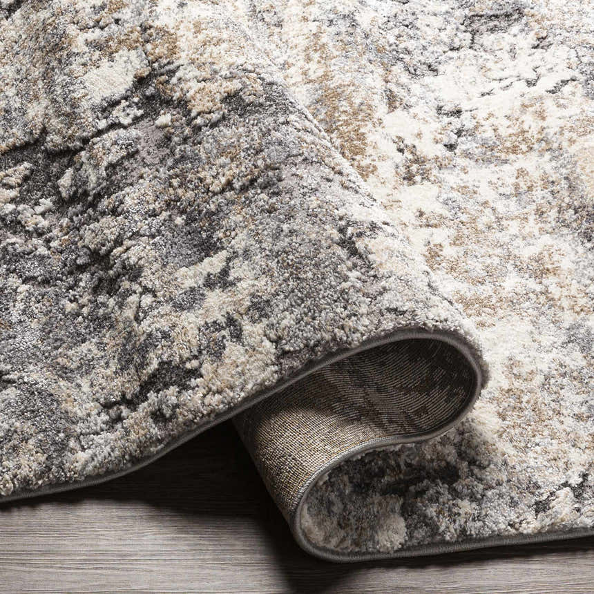 Close-up of the thick Satsop Rock Pattern Rug. Features black, charcoal, gray, ivory, and tan colors with a contemporary design. Fold