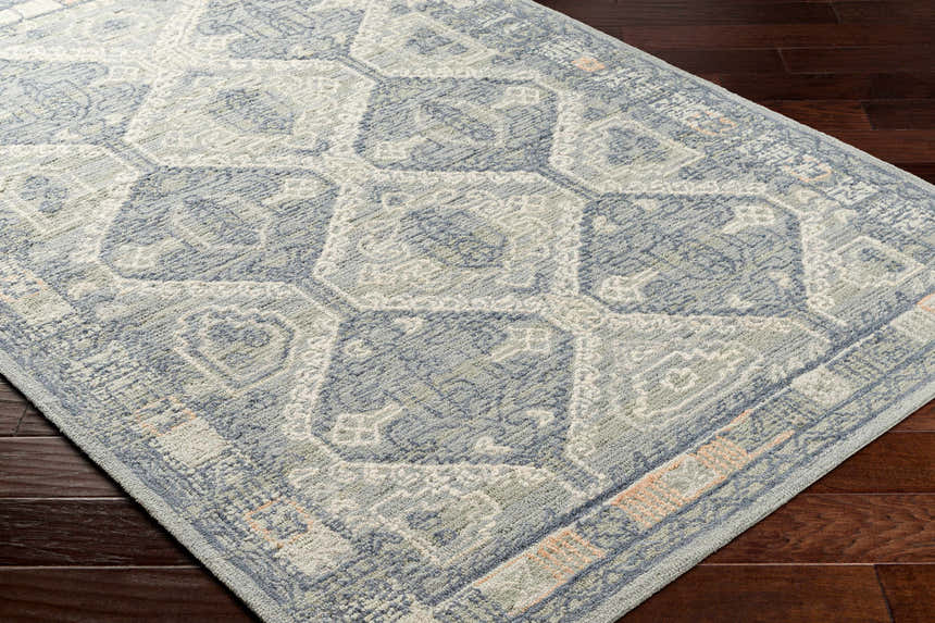 Close-up of the Doman Area Rug showing its traditional geometric pattern and wool texture in gray, blue, and cream. Corner