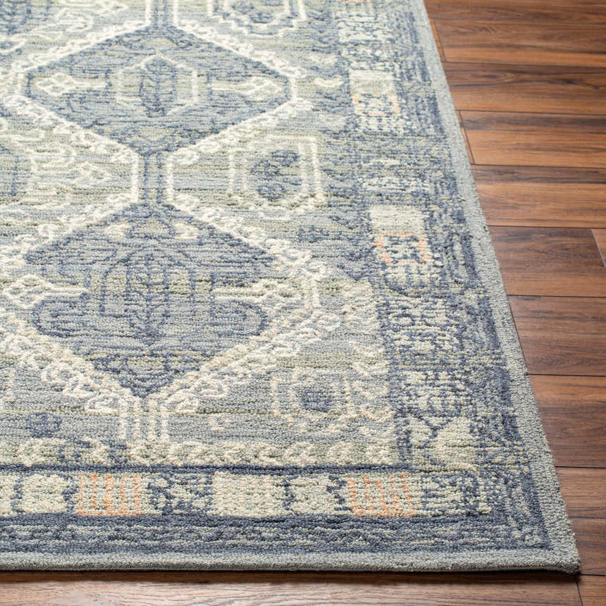 Close-up of a hand-tufted Doman Area Rug. Farmhouse style rug in dark brown, gray, and cream on a wood floor. Front