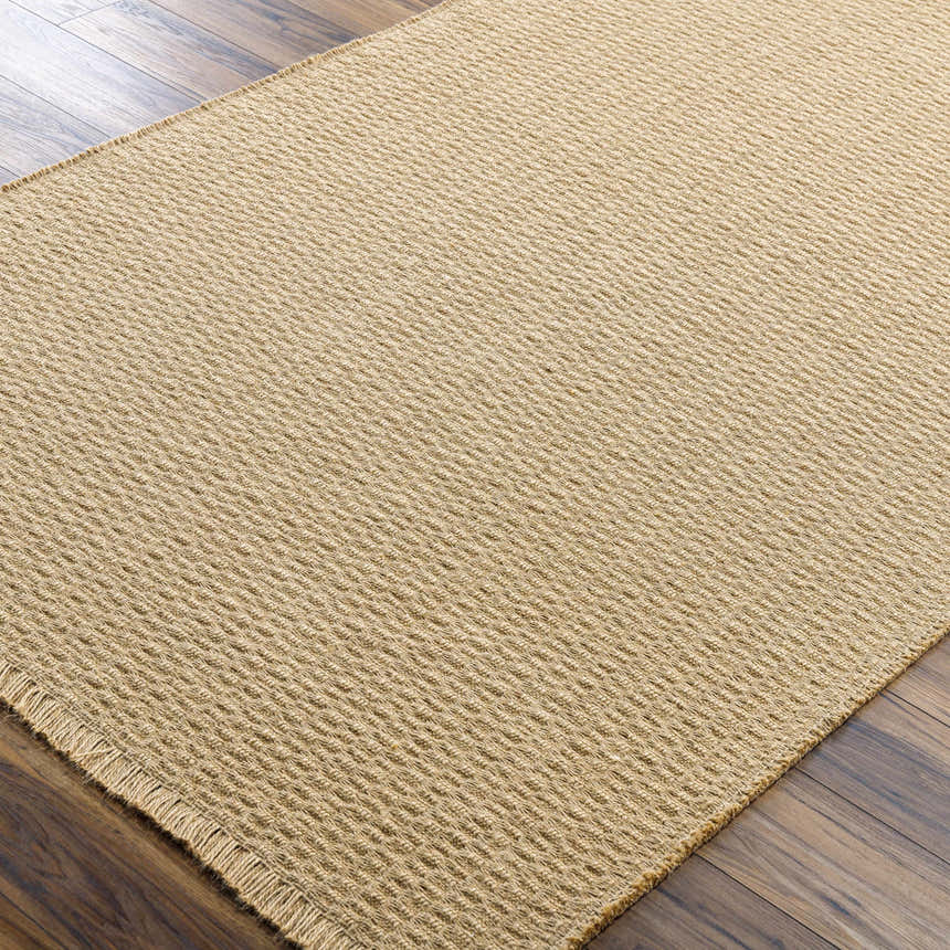 Close-up of the textured Kimi Jute Area Rug in light brown and camel on a dark hardwood floor. Corner