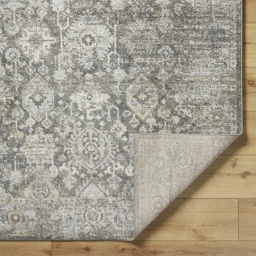 Close-up of the Strom Area Rug showing its traditional, distressed pattern in blue, charcoal, cream, and gray. Fold