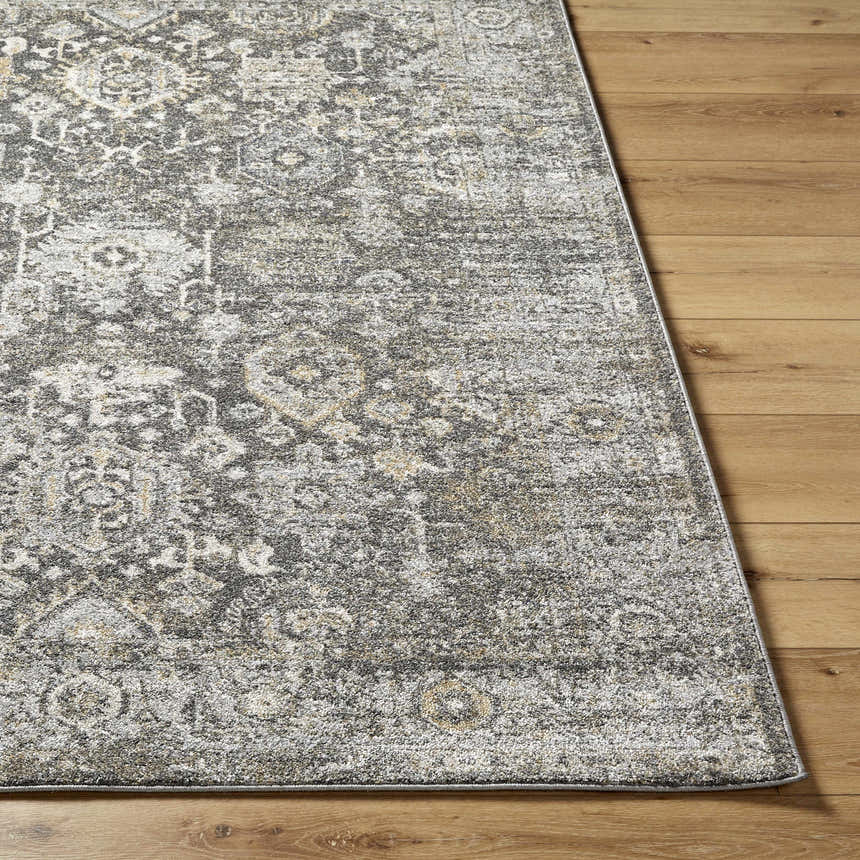 Close-up of the Strom Area Rug showing a traditional gray, cream, and mustard pattern on a wood floor. Front