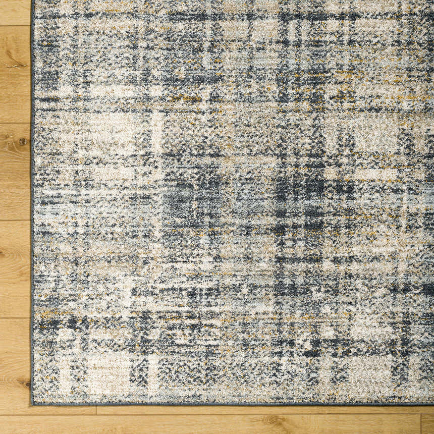 Close-up of the Kenny Area Rug showing its abstract plaid pattern in shades of gray, ivory, and gold on a wood floor. Corner
