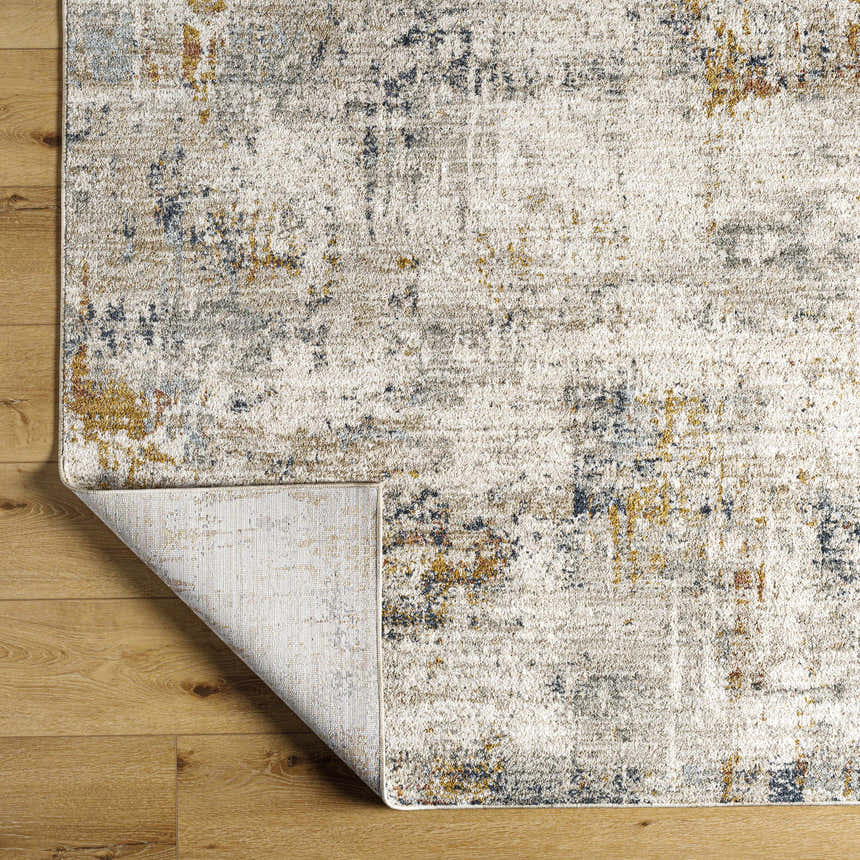 Close-up of the Leela Area Rug showing its light gray, natural gray, blue and gold contemporary design and texture. Fold