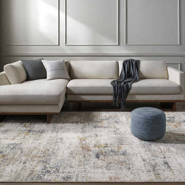 Living room scene with a light gray Leela Area Rug, beige sectional sofa, and gray knit ottoman. Roomscene-Rectangle