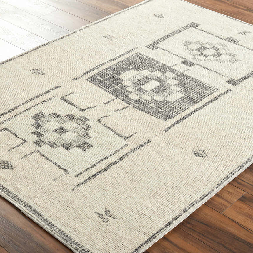 Close-up of the Solana Medallion Charcoal rug. Beige rug with a charcoal gray geometric medallion pattern. Farmhouse style. Corner