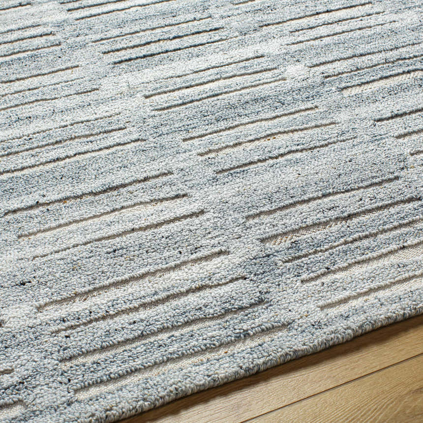 Close-up of the hand-tufted Darcy Area Rug, featuring a textured stripe pattern in light blue and cream. Texture