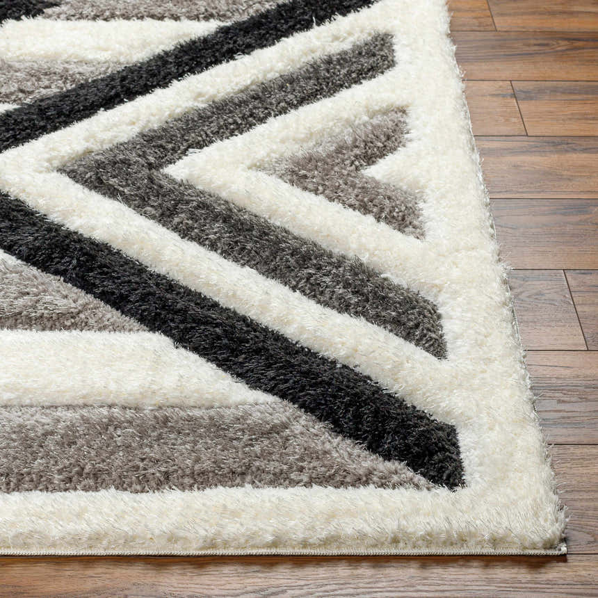 Close-up of the Abeje Black & White Area Rug showing its geometric shag design and soft texture on a wood floor. Front