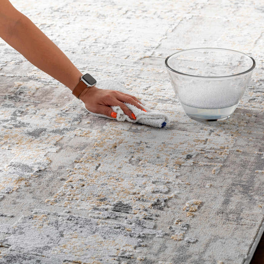 Close-up of the Schaefferstown Area Rug being cleaned; charcoal, gray, beige, and white abstract pattern. Swatch