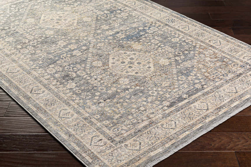 Close-up of the traditional Artan Area Rug in dark brown, gray, and natural tones on a dark wood floor. Corner
