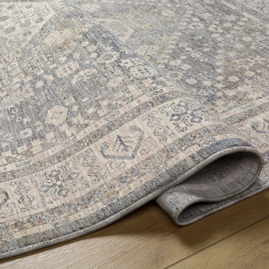 Close-up of the Artan Area Rug, a traditional design in gray, light gray, and natural tones. Machine woven polyester rug texture. Fold