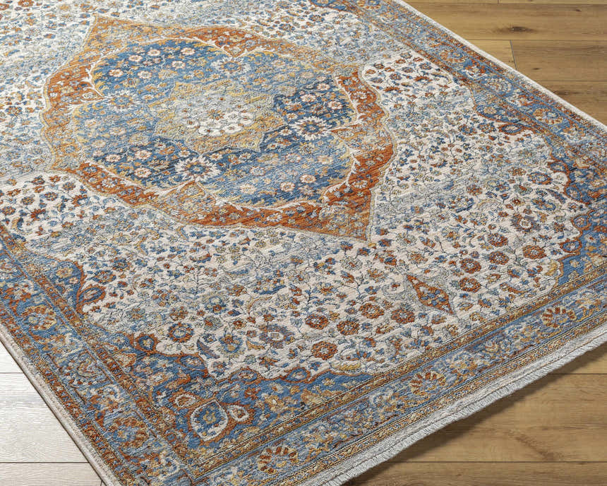 Close-up of the Bojan Area Rug in Beachhouse. Features traditional floral patterns in blue, brown, and copper tones. Corner
