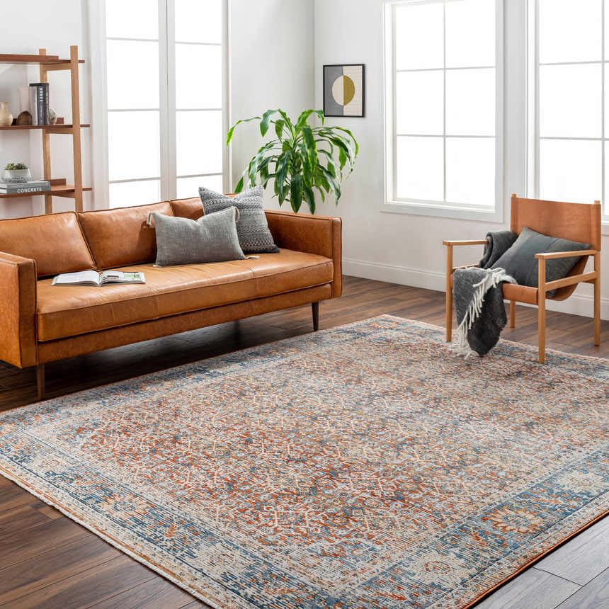 Living room scene with a clay and denim Dalit Area Rug, leather sofa, and wood accents. Roomscene-Rectangle