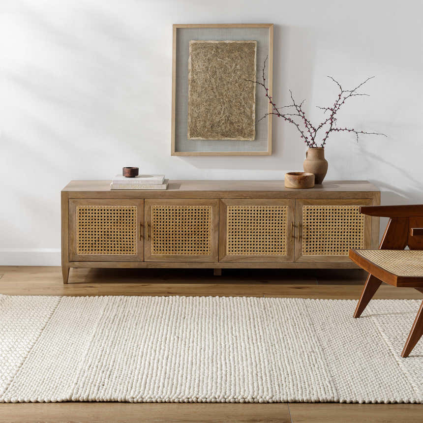 Living room scene with a Nimai Cream Wool Area Rug, wood cabinet, and modern chair on a wood floor. Roomscene-Rectangle