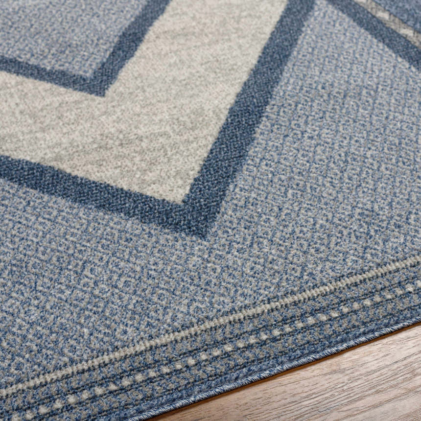 Close-up of the Onan Area Rug. Farmhouse style rug in arctic sky, gray, and silver with a geometric pattern. Texture