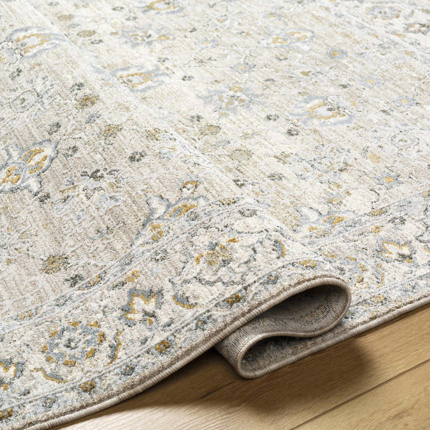 Close-up of the Amaru Cream & Sage Textured Rug. Features a traditional floral pattern in cream, sage, gray, and mustard tones. Fold