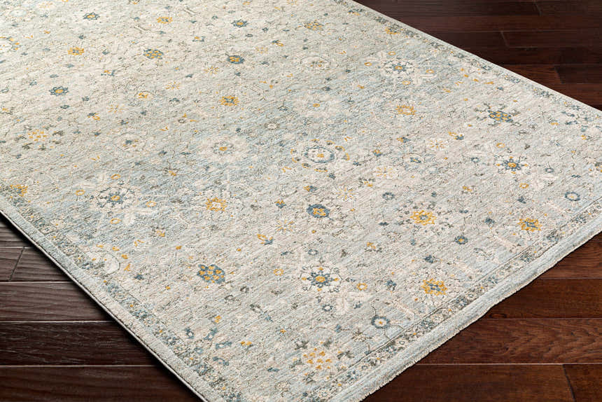 Close-up of the Annie Green Textured Rug with Fringes. Features a farmhouse style floral pattern in green, blue, and yellow. Corner