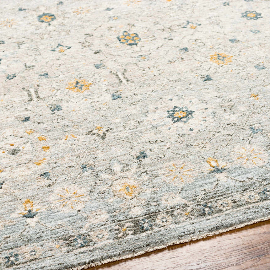 Close up of the Annie Green Textured Rug. Features a floral pattern with blue and gold accents on a light background. Texture
