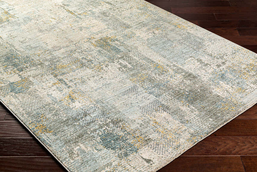 Close-up of the Elina Textured Abstract Rug. Features dusty sage, ink blue, light gray, and mustard hues. Corner