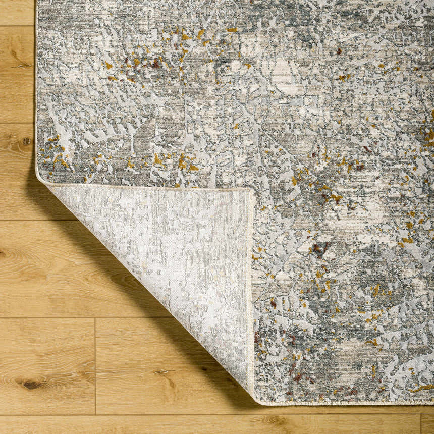 Close-up of Moke Textured Rug in gray, camel, and clay on wood floor, showing abstract design and construction. Fold