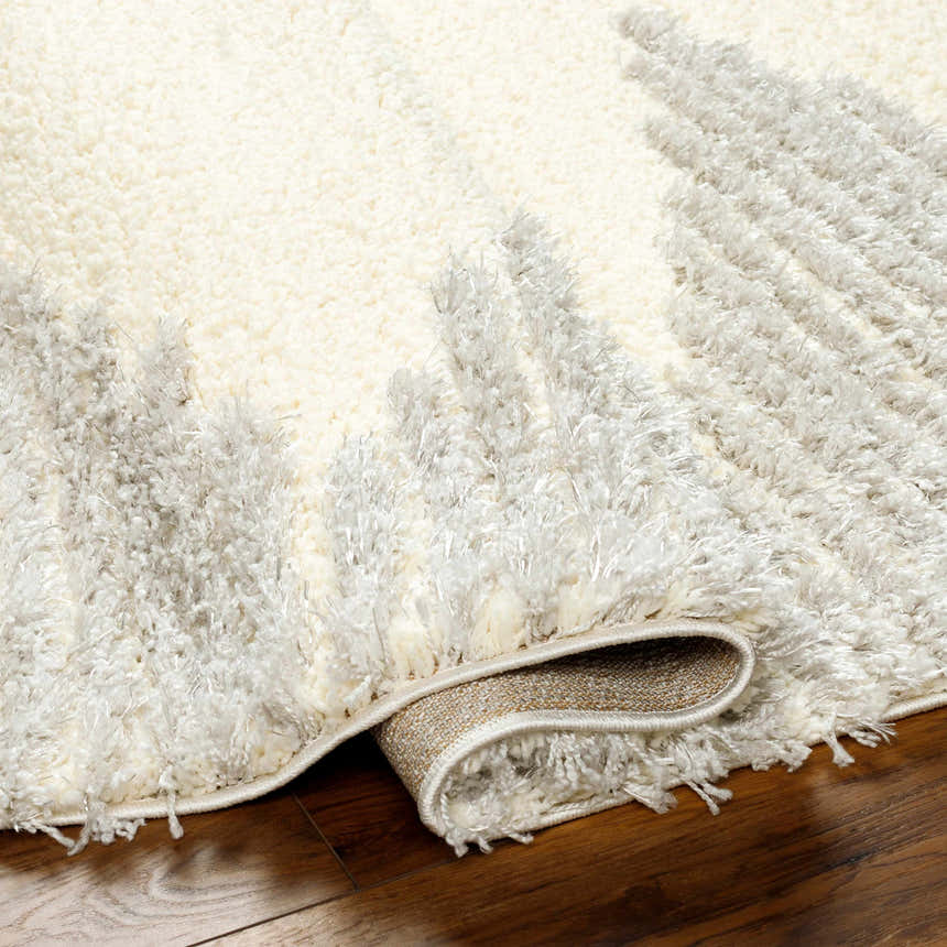 Close-up of the plush Bayan Gray Area Rug showing its beige and gray shag texture and machine woven construction. Fold