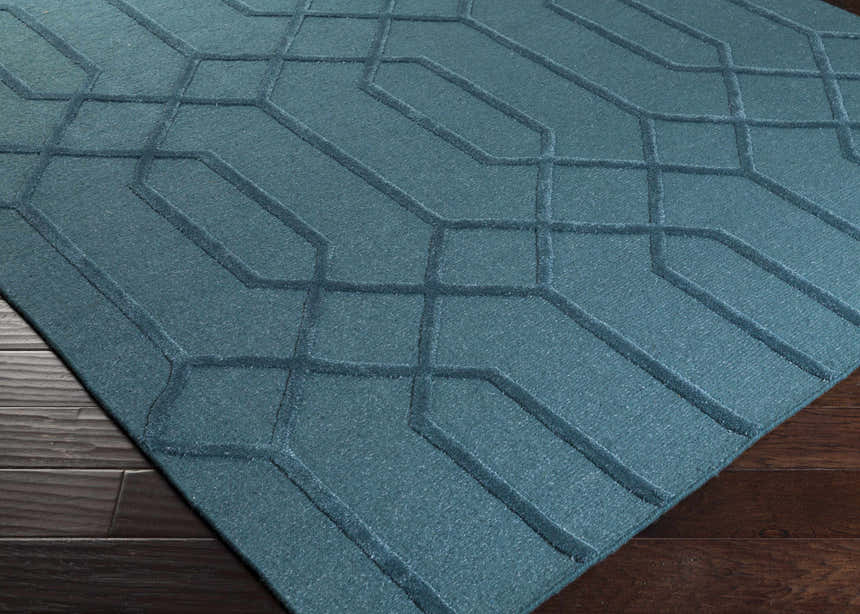 Close-up of the teal Sharps Area Carpet. Hand-knotted wool rug with a geometric pattern and subtle texture. Corner