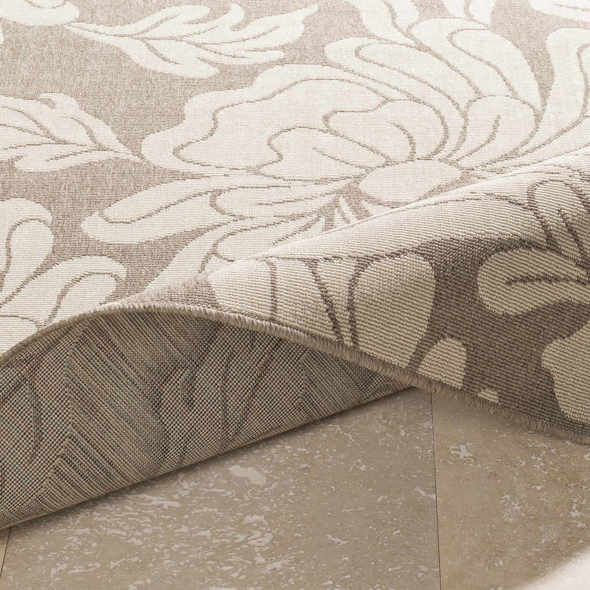 Close-up of the Sherard Area Rug showing beige floral pattern and durable machine-woven construction. Fold