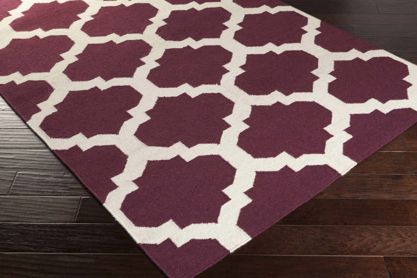 Close-up of the Shotton Area Carpet. Dark purple wool rug with an ivory geometric trellis pattern. Hand woven. Corner