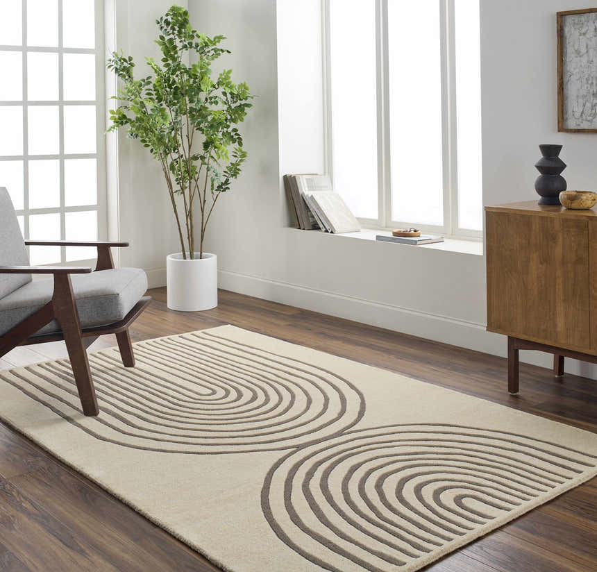 Living room scene with a Fuat Beige Area Rug, gray chair, wood cabinet, and large window. Roomscene-Rectangle
