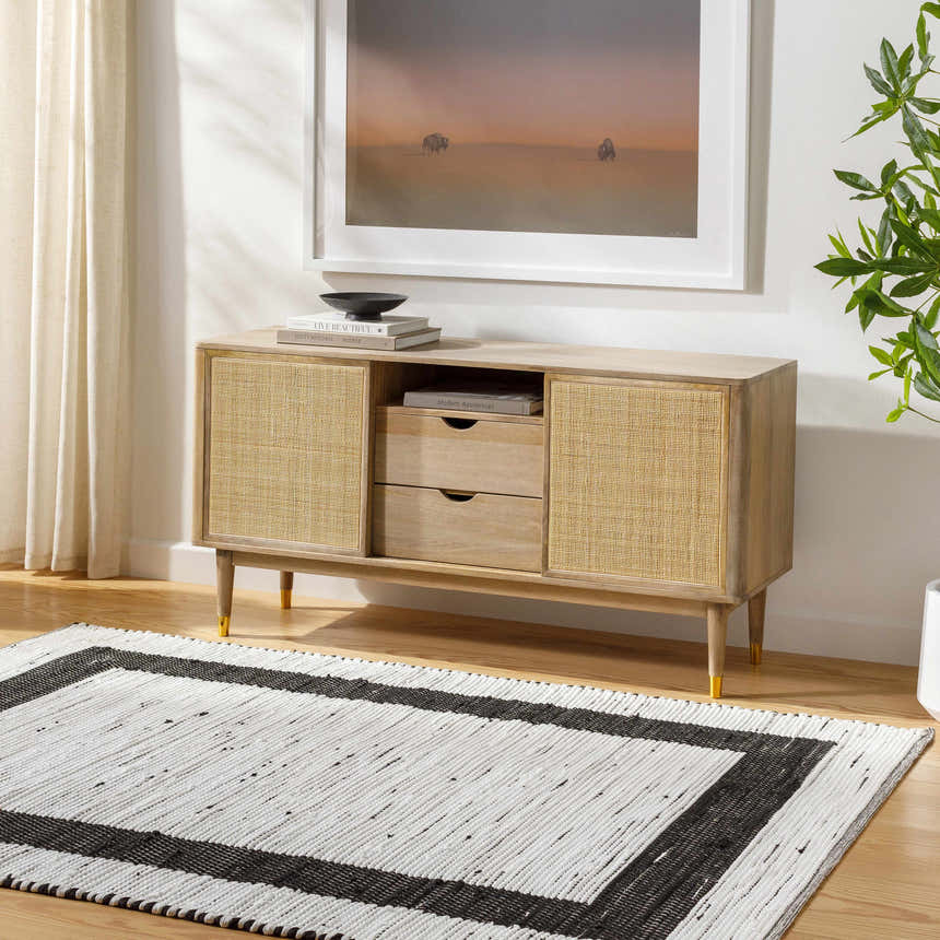 Living room scene with a charcoal and off white Jaden Area Rug, wood floors, and a light wood console table. Roomscene-Rectangle