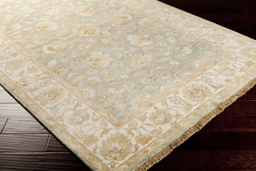 Close-up of the Skipwith Area Carpet, a hand-knotted wool rug with a traditional floral pattern in soft green and beige tones. Corner