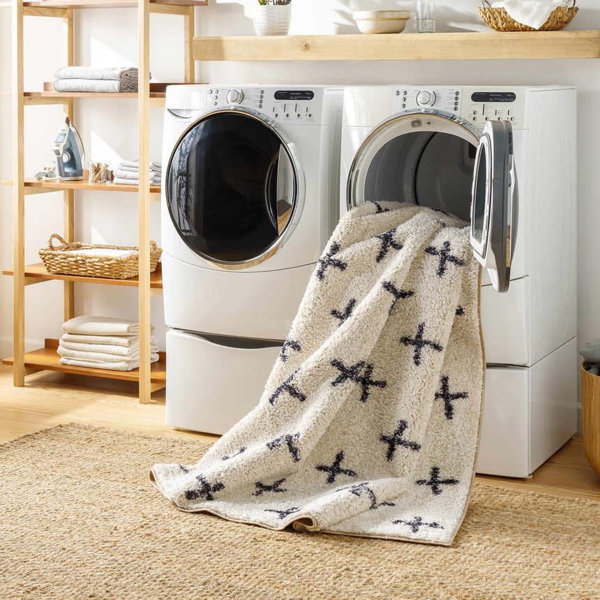 Laundry room scene with the beige Bede Washable Area Rug in the dryer, showcasing its easy-to-clean feature. Washing-Machine