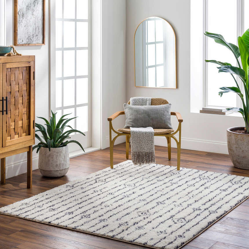 Bright room with a Demi Beige Washable Area Rug, wood floors, chair, cabinet, and plants. Roomscene-Rectangle
