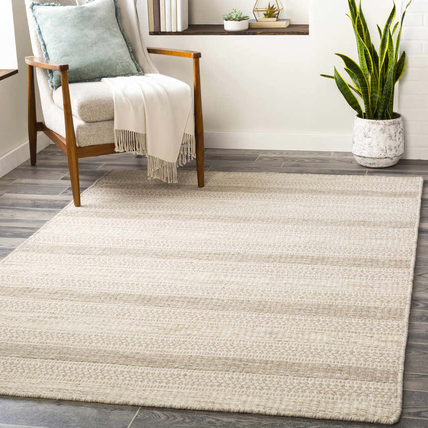 Living room scene with a Silverthorne wool area rug, chair with throw, and snake plant. Cream and gray tones. Roomscene-Rectangle