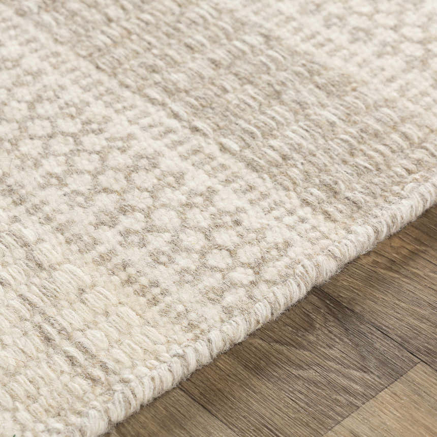 Close-up of the Silverthorne Wool Area Rug. Cream and medium gray woven rug texture on a wood floor. Texture