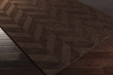 Close-up of the dark brown Summertown Area Rug, a hand-loomed wool rug with a contemporary geometric chevron pattern. Corner